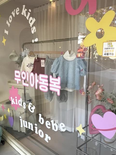 「무인아동복」 글씨가 붙은 쇼윈도 안 마네킹과 아이 옷
